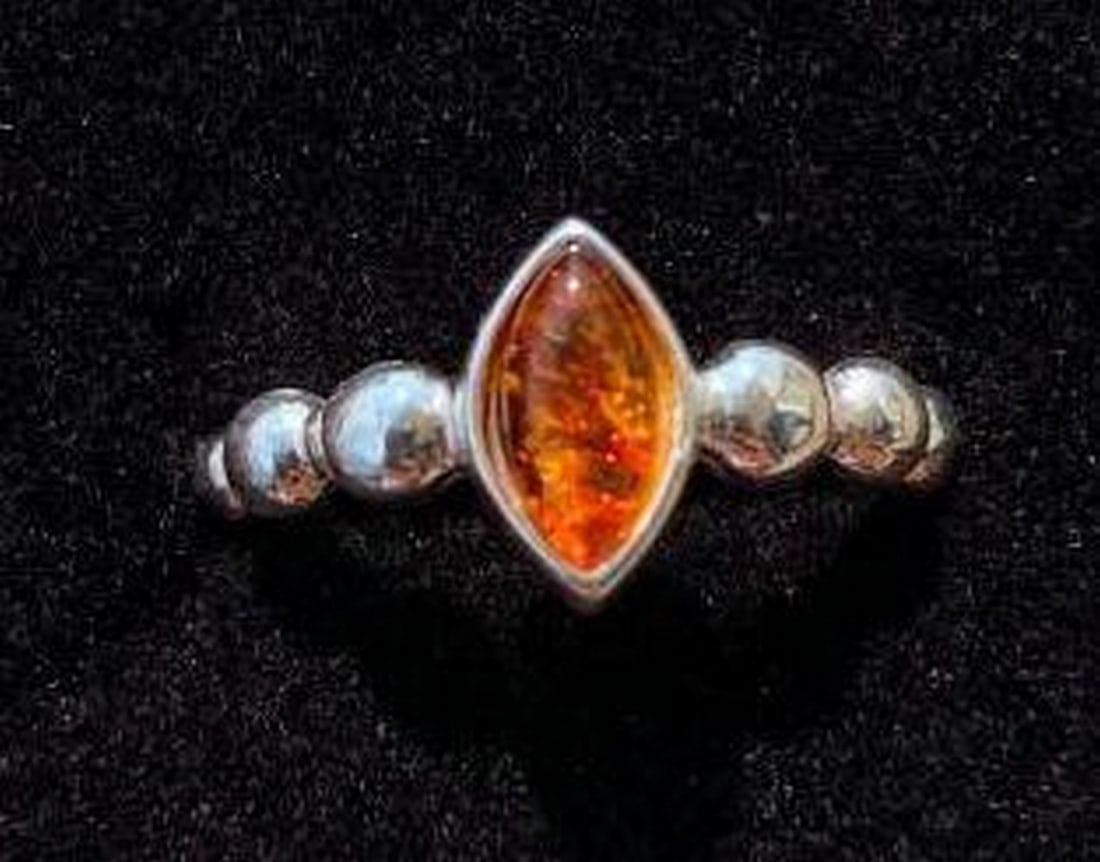 Sterling Silver Ring with Marquise Cut Amber Stone: Sterling Silver Ring with Marquise Cut Amber Stone This elegant sterling silver ring showcases a stunning marquise-cut amber stone at its center, exuding warmth and natural beauty. The sides of the b