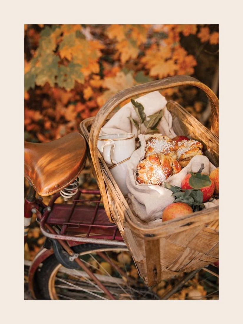 Cozy Autumn Picnic Poster Print: Cozy Autumn Picnic Poster A cozy autumn poster featuring a red bike with a wicker basket filled with apples, pastries, and a white mug. Yellow and green leaves in the background enhance the warm, sea
