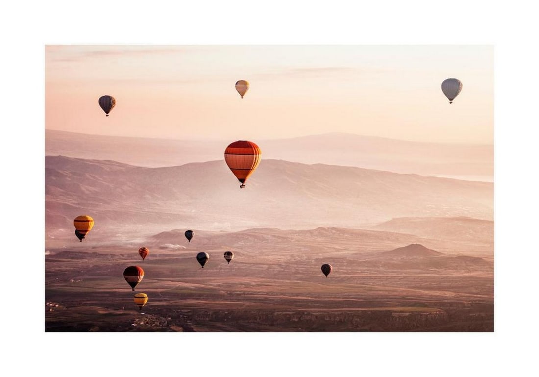 Sunrise Balloon Ride Poster: Sunrise Balloon Ride Poster A landscape print featuring colorful hot air balloons drifting over mountains at sunrise. The interplay of the sun’s first rays with the vibrant balloons creates a striki