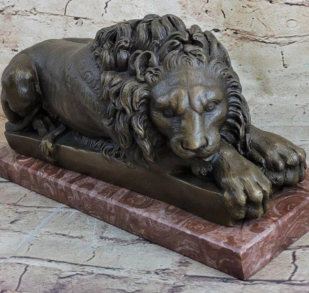 Resting King of the Jungle Bronze Statue - 7" x 12.5": Resting King of the Jungle Bronze Statue - 7" x 12.5" This impressive sculpture captures the regal essence of a lion engaged in a moment of self-care and poise. The reclined lion is portrayed
