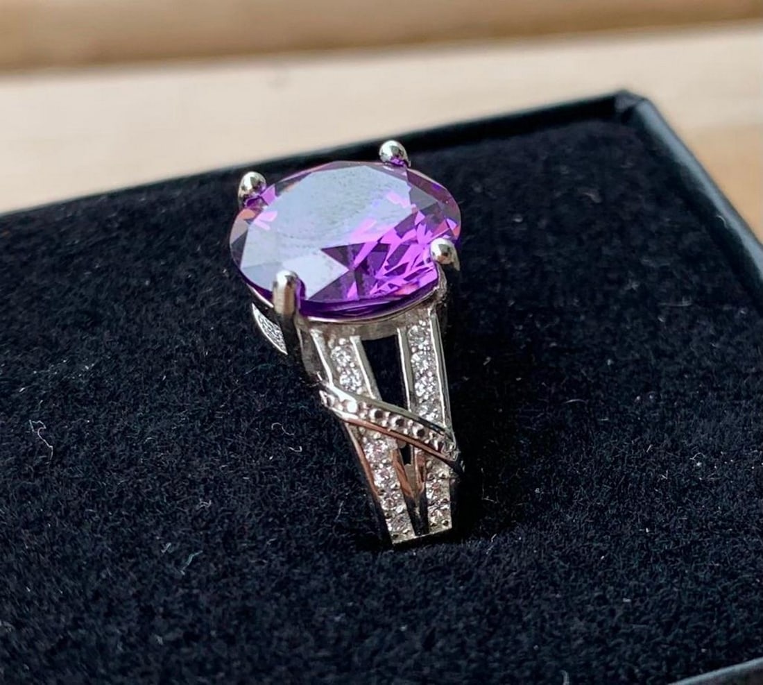 Sterling Silver Ring with Round Amethyst: Sterling Silver Ring with Round Amethyst This elegant sterling silver ring showcases a vibrant round-cut amethyst at its center, radiating a rich purple hue that catches the light beautifully. Subtle