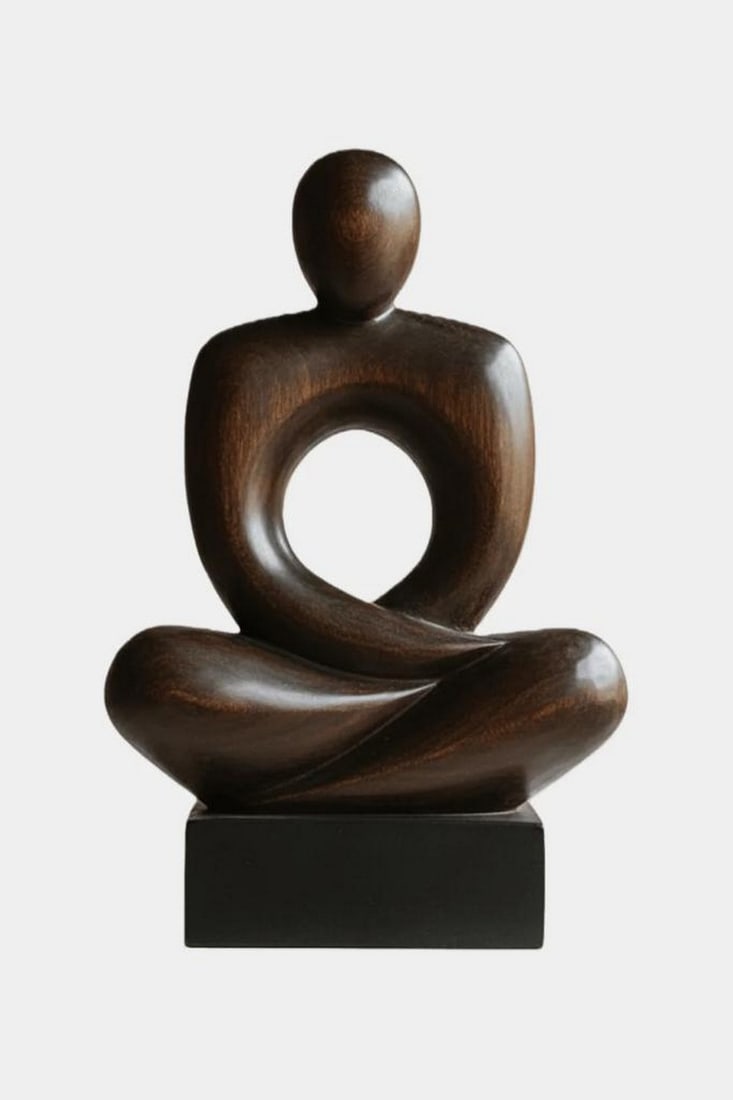 Seated Abstract Meditation Sculpture: Seated Abstract Meditation Sculpture A modern sculpture of a seated figure in a meditative pose, defined by smooth curves and minimalist form. Crafted from dark polished wood, the stylized figure