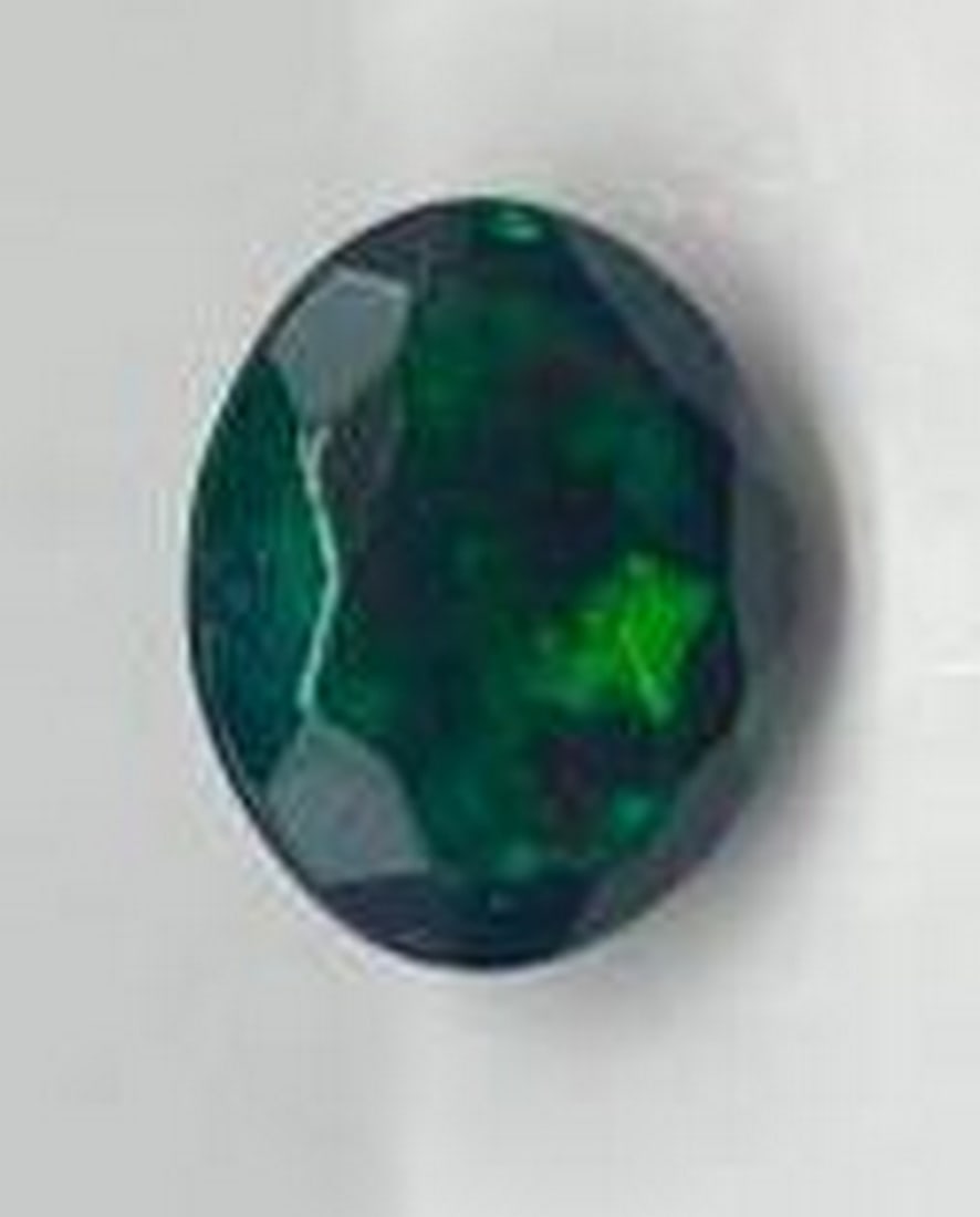 Oval Facet Black Opal Gemstone: Oval Facet Black Opal Gemstone This is a mesmerizing piece, showcasing a dark, mysterious base with vibrant flashes of iridescent color. This gemstone is perfect for creating unique, statement