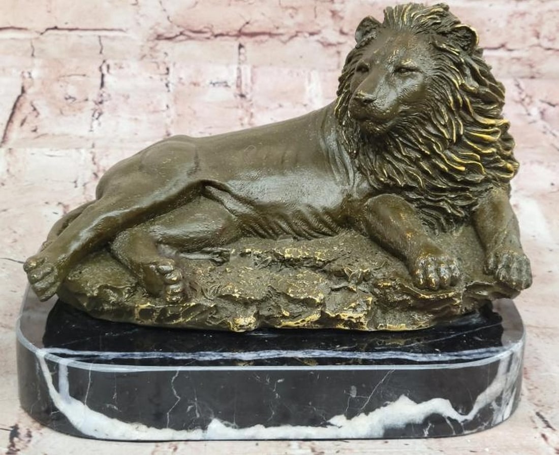 Majestic Rest: Reproduction Bronze Reclining Lion Statue: Majestic Rest: Reproduction Bronze Reclining Lion Statue Exuding regal strength in a moment of calm, this reproduction bronze sculpture features a magnificent lion in a reclining pose, alert yet comp