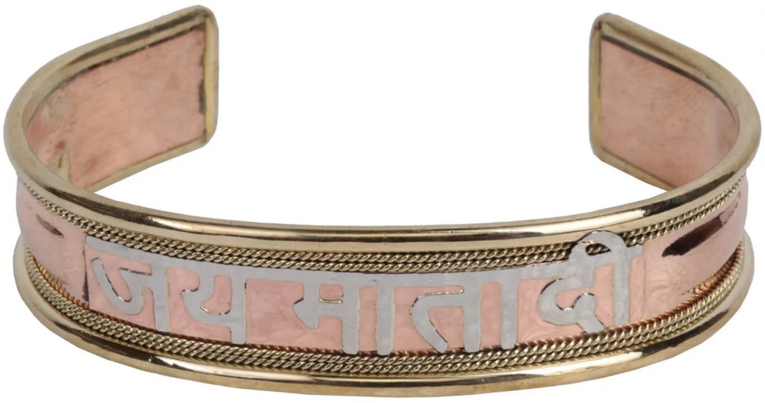 Jai Mata Di Cuff Bracelet: Jai Mata Di Cuff Bracelet This copper alloy cuff bracelet features the sacred inscription “Jai Mata Di,” honoring the divine Mother. The adjustable design ensures a comfortable fit, while the