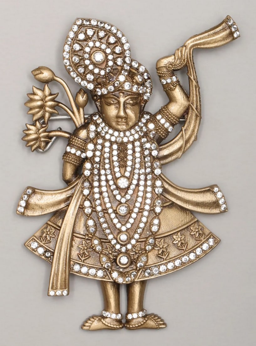 Blessings of Shrinathji Brooch: Blessings of Shrinathji Brooch This beautifully crafted brooch embodies the divine essence of Shrinathji with elegance and charm. Made from brass, its warm tones complement the shimmering stones that