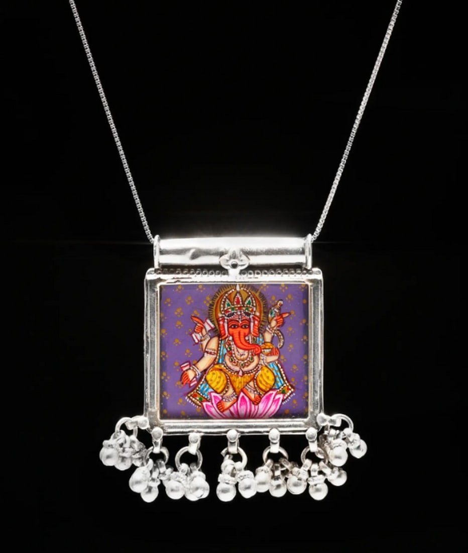 Sacred Square Ganesha Pendant: Sacred Square Ganesha Pendant This sterling silver pendant showcases a hand-painted image of Lord Ganesha, symbolizing new beginnings and the removal of obstacles. Set within a square frame, the
