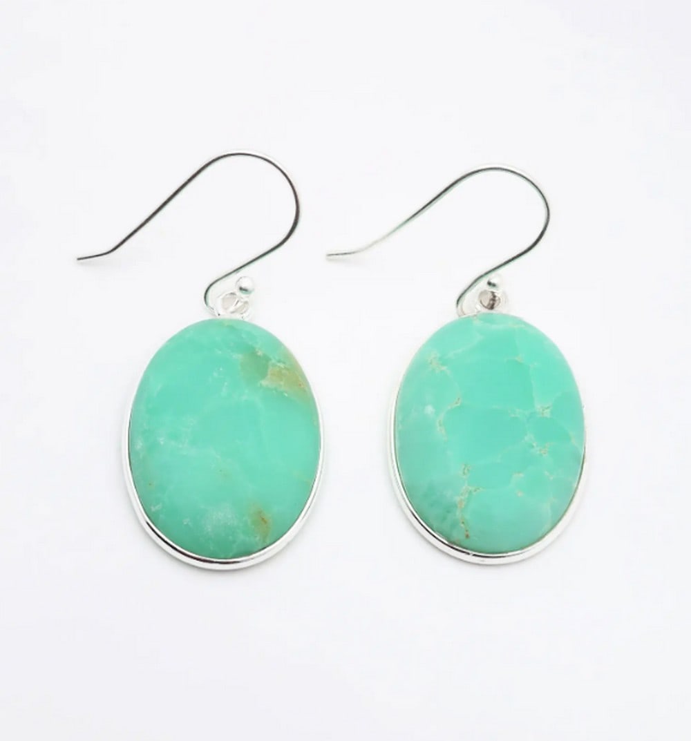 Verdant Glow Chrysoprase Hooks: Verdant Glow Chrysoprase Hooks These oval-shaped chrysoprase gemstone hook earrings showcase vibrant sea-green hues, set in delicate sterling silver frames for timeless elegance. Their polished