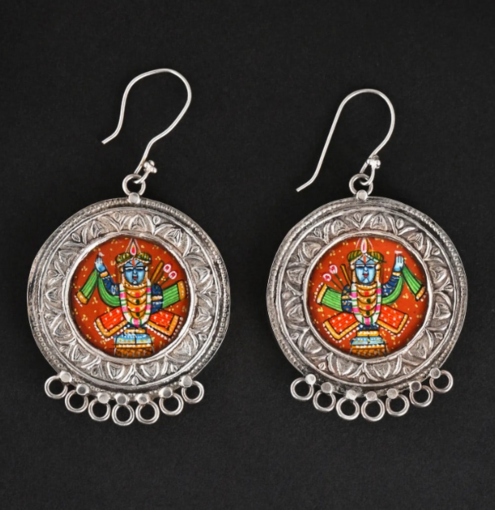 Divine Shrinathji Hook Charms: Divine Shrinathji Hook Charms These sterling silver earrings feature a hand-painted miniature of Shrinathji, capturing India’s rich artistry and heritage. Vibrant colors and intricate details