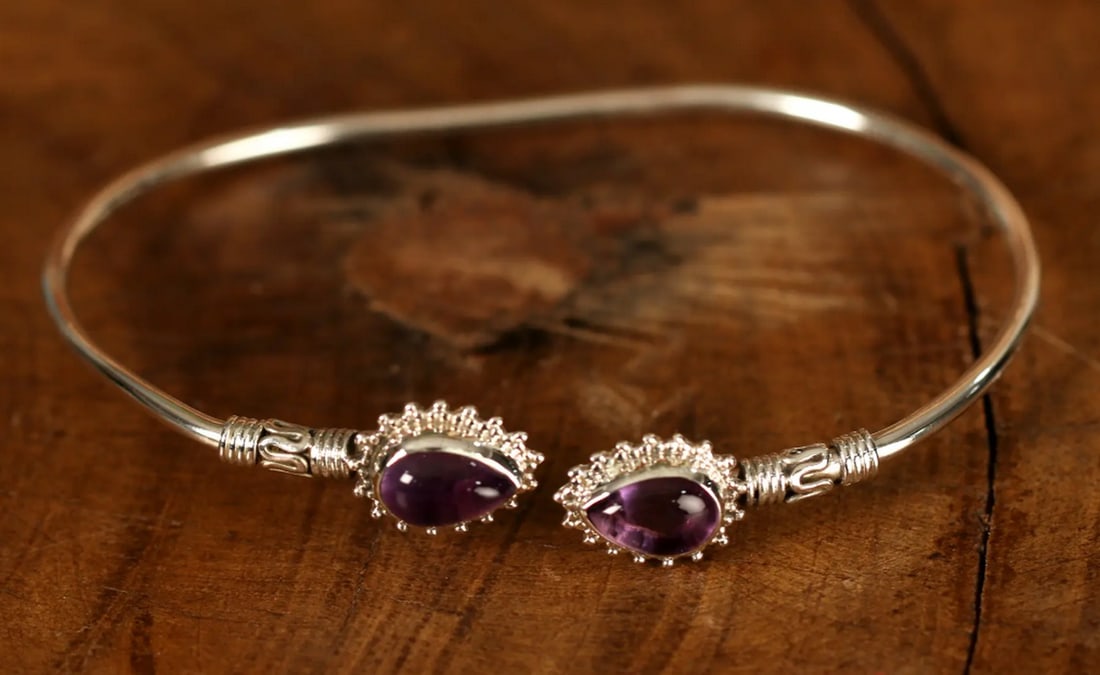 Twin Gemstone Sterling Silver Statement Bracelet: Twin Gemstone Sterling Silver Statement Bracelet This striking sterling silver bracelet blends contemporary design with cultural flair. Featuring two vibrant amethyst stones and intricate