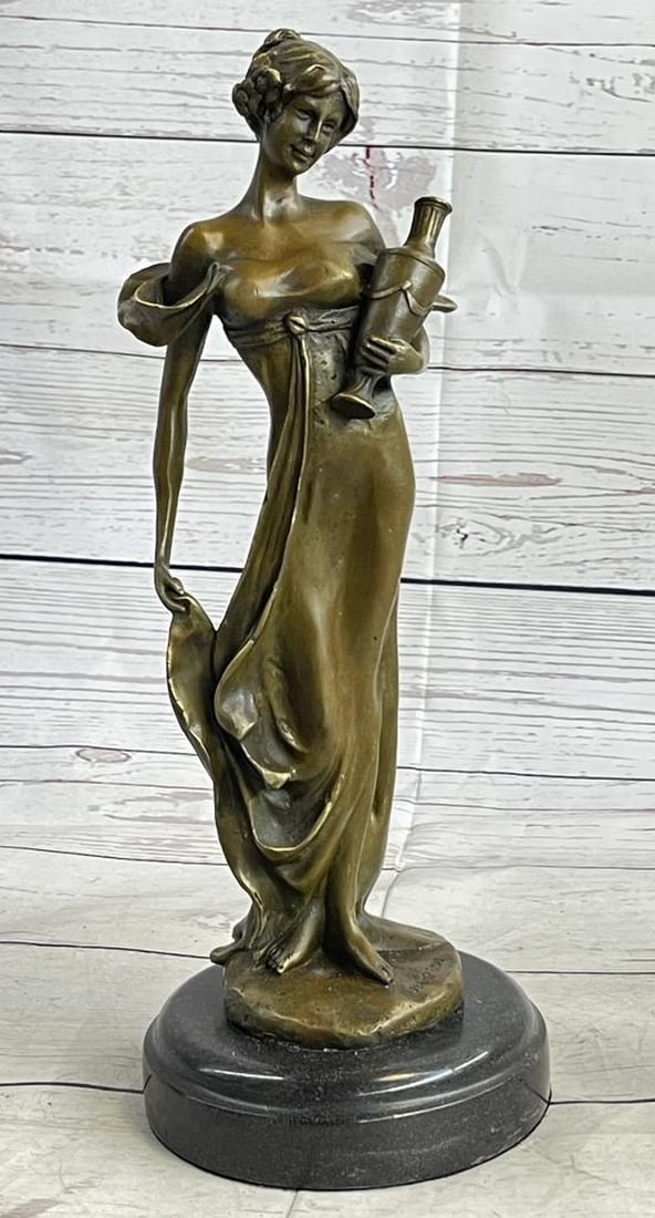 Woman Holding Vase Bronze Sculpture: Woman Holding Vase Bronze Sculpture This classical maiden stands in an upright position, cradling an empty vase at her side with one hand, holding the bottom of her dress of the ground with her other
