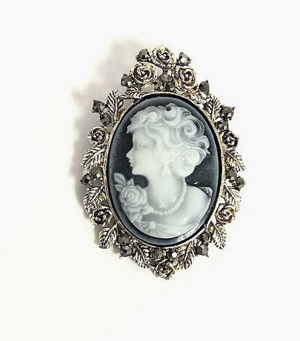 Victorian-Style Cameo Brooch: Victorian-Style Cameo Brooch This elegant brooch features a carved Victorian-style cameo of a woman. The outer edge is adorned with sparkling black gemstones and intricate floral detailing, creating
