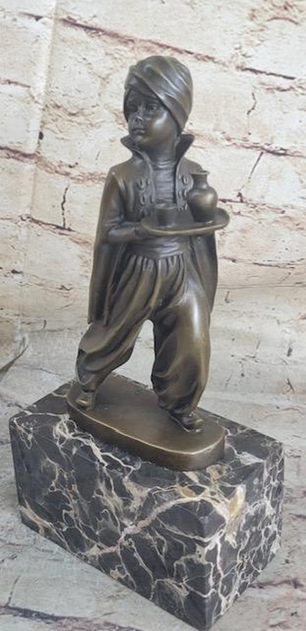 Arabian Boy Carrying Vase Inspired Bronze Statue - 10" x 5": Arabian Boy Carrying Vase Inspired Bronze Statue - 10" x 5" In a majestic palace, a young Arabian boy serves as a servant, carrying a small waiter with a round bottle to quench his master'