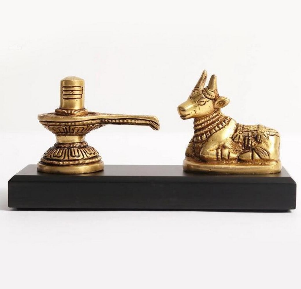 6" Small Shivalinga with Nandi on Wooden Base: 6" Small Shivalinga with Nandi on Wooden Base This 6" brass and wood statue beautifully depicts a Shivalinga accompanied by Nandi, symbolizing the cosmic energy and divine presence of Lord Sh
