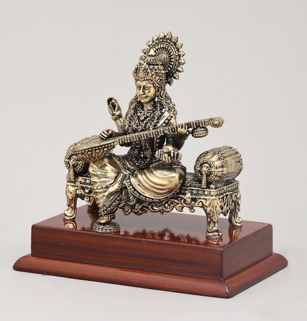 5" Goddess Saraswati Seated on Wooden Base Brass Idol: 5" Goddess Saraswati Seated on Wooden Base Brass Idol This 5" brass idol beautifully depicts Goddess Saraswati, the Hindu deity of knowledge, music, art, and learning, seated gracefully on a