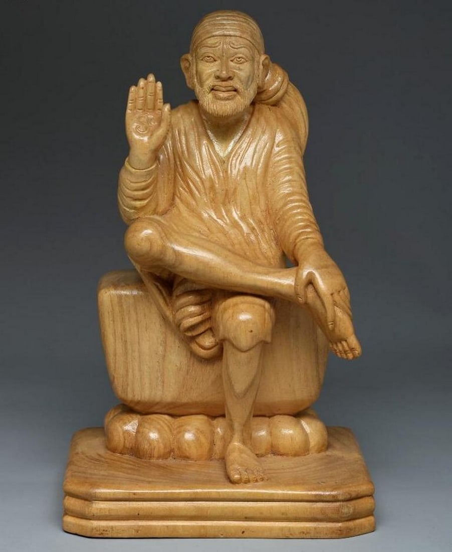 12" Sai Baba Seated in Blessing Hand Carved Wooden Statue: 12" Sai Baba Seated in Blessing Hand Carved Wooden Statue This beautifully crafted wooden sculpture portrays Sai Baba seated in a peaceful, composed posture with his hand raised in blessing, a
