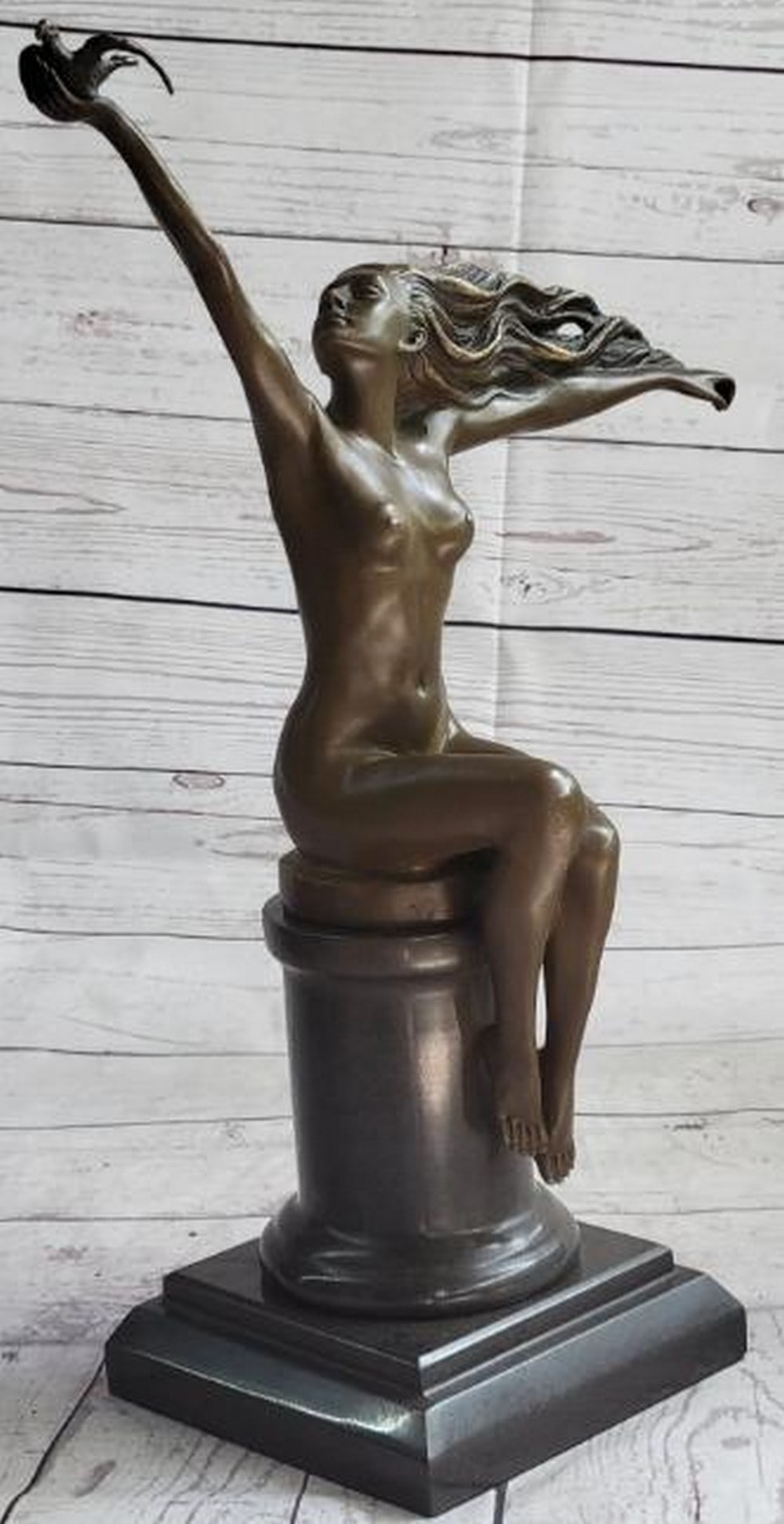Nude Girl with Bird Bronze Sculpture: Nude Girl with Bird Bronze Sculpture Delicate and serene, this reproduction bronze sculpture depicts a nude girl seated gracefully atop a classical pillar, holding a bird, likely a pigeon or dove, ge