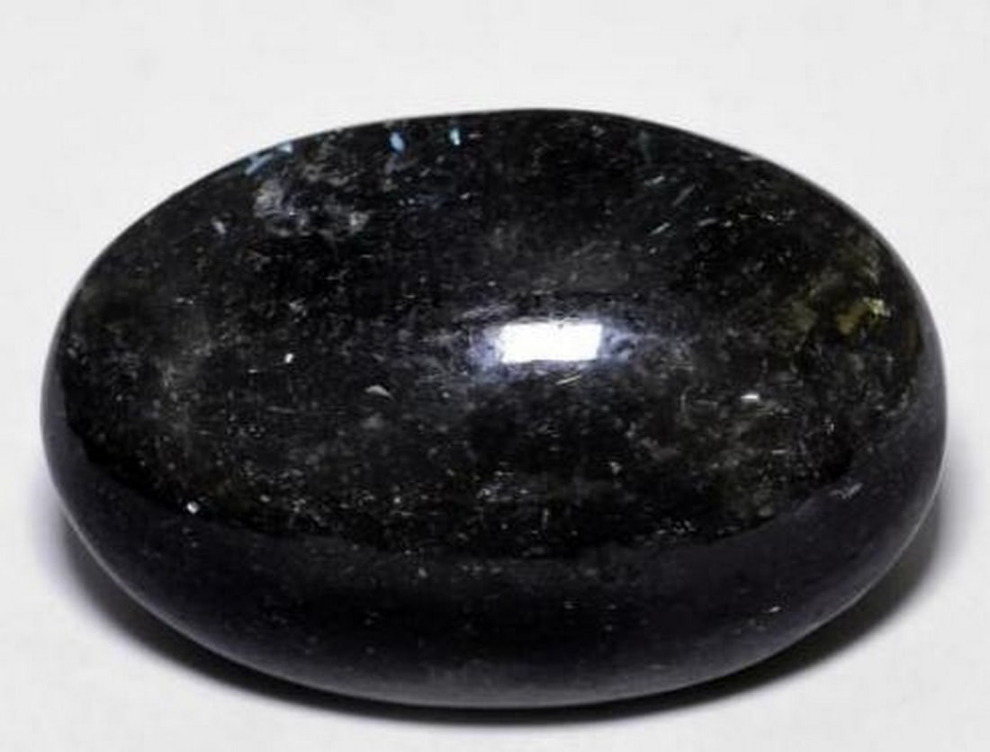Black Nuummite Oval Cabochon Gemstone with Blue Sparkle: Black Nuummite Oval Cabochon Gemstone with Blue Sparkle This captivating loose gemstone is a polished oval cabochon of Nuummite, featuring a deep black base with mesmerizing blue sparkles that