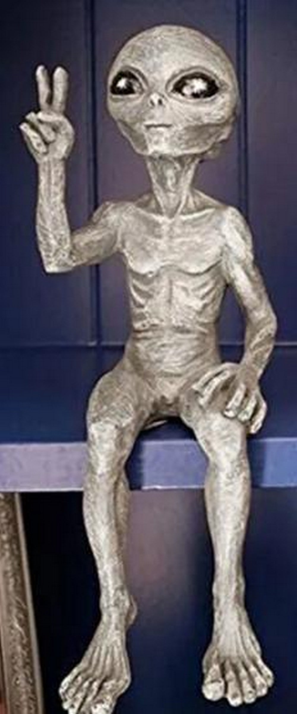 Peace Visitor Alien Resin Sculpture: Peace Visitor Alien Resin Sculpture Playful and otherworldly, this resin sculpture features a seated alien figure flashing the iconic peace sign. With its elongated limbs, oversized head, and smooth,