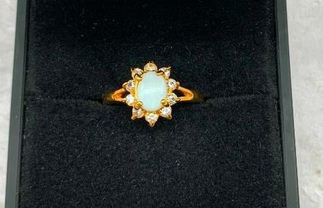 Yellow Gold Electroplated Ring with White Opal & Crystal Halo: Yellow Gold Electroplated Ring with White Opal & Crystal Halo This stunning ring exudes classic elegance with a touch of ethereal beauty. At its center sits a luminous white opal gemstone, radiat