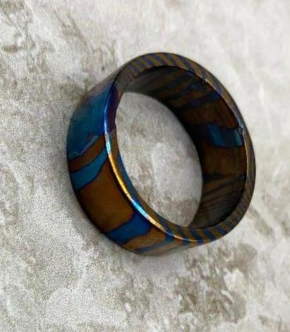 Timascus Ring Blue & Orange Swirl with Smooth Rounded Edges: Timascus Ring Blue & Orange Swirl with Smooth Rounded Edges This striking ring showcases fluid swirls of vivid blue and fiery orange, creating a dynamic, iridescent finish that shifts with the