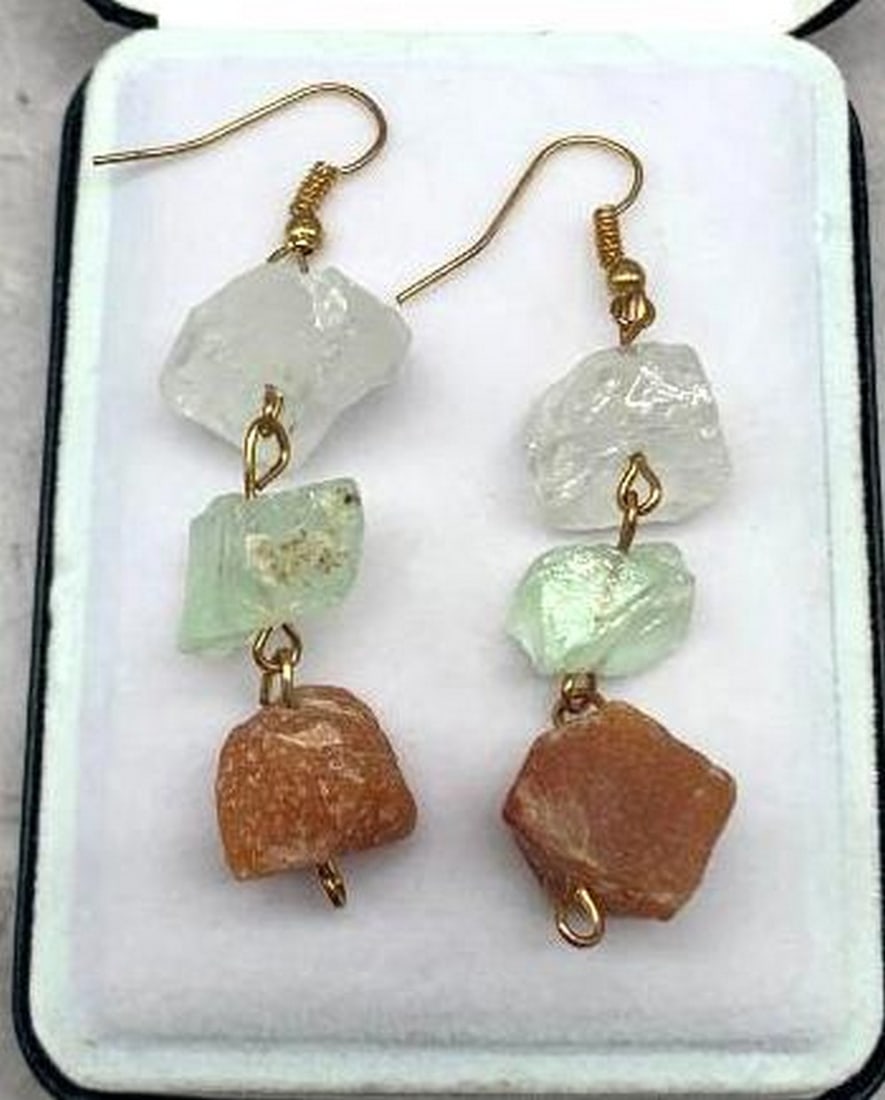 Asymmetric Triple-Stone Dangle Earrings: Asymmetric Triple-Stone Dangle Earrings These earrings make a bold, organic statement with their trio of raw, asymmetrically set stones. Dangling gracefully, each earring features a clear stone at