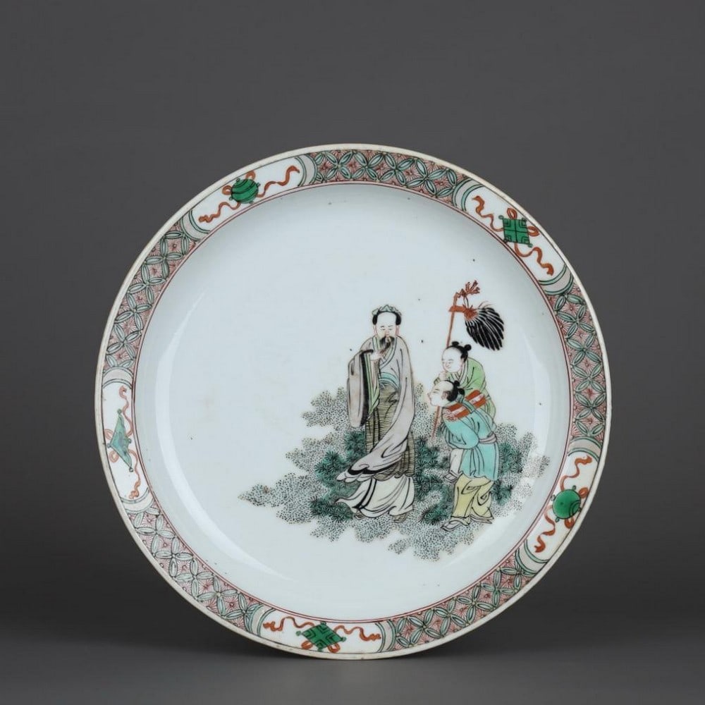 Famille Verte Figure Plate: Famille Verte Figure Plate A captivating famille verte porcelain figure plate, showcasing vibrant green and multicolored enamel work. The central scene features intricately painted figures, perhaps f