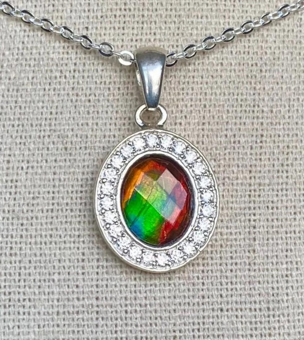 Faceted Ammolite Pendant with CZ Halo in Heavy Sterling Setting: Faceted Ammolite Pendant with CZ Halo in Heavy Sterling Setting This ammolite pendant features a 10mm x 8mm faceted quartz-capped triplet in red, green, and hints of teal. The gem is set in a