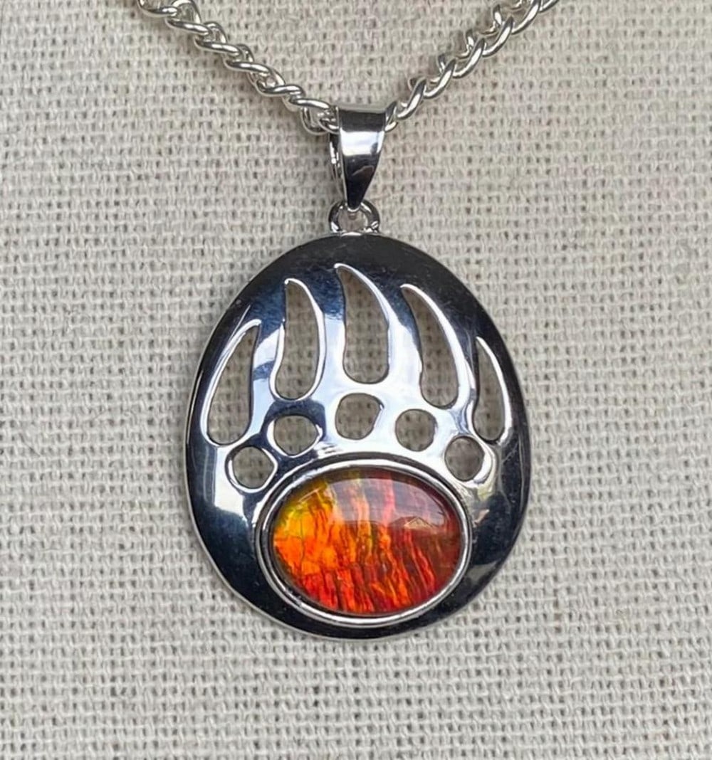 Ammolite Bear Paw Pendant: Ammolite Bear Paw Pendant This ammolite pendant features a 10mm x 8mm quartz-capped triplet in a rich rusty red, which shifts to green at extreme angles. The gem is set in a bear paw-inspired