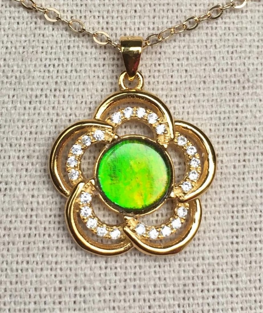 Bright Green Ammolite Pendant with Flower Design and CZ Accents: Bright Green Ammolite Pendant with Flower Design and CZ Accents This ammolite pendant features a vibrant, lighter green stone with subtle gold tones. The 12mm x 10mm low dome quartz-capped triplet is