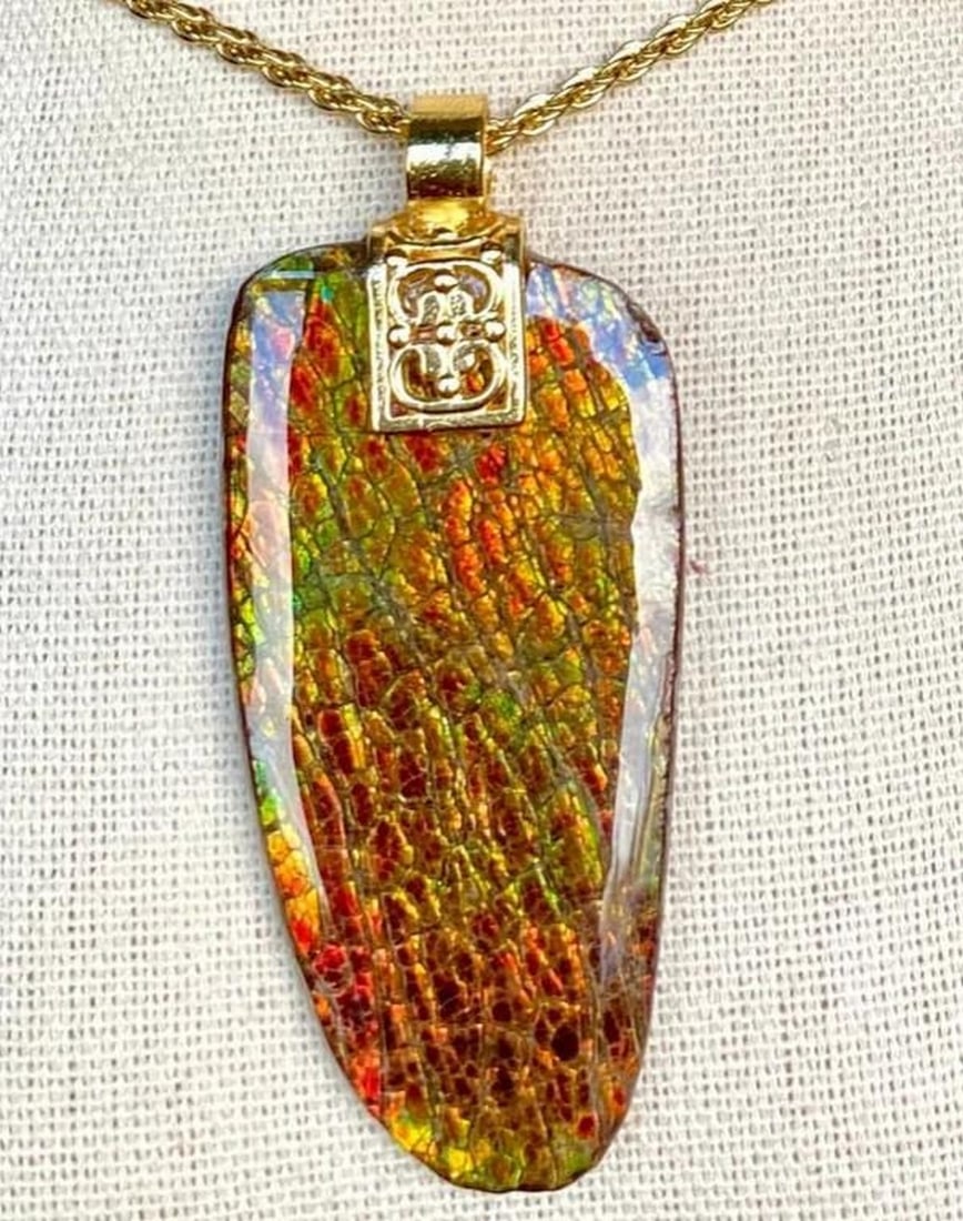 Golden Relic Ammolite Pendant: Golden Relic Ammolite Pendant This is an ammolite pendant with a large gemstone in autumn colors. It has a shiny resin coating. The gem hangs from a Bali style bail with a gold overlay (no zinc,