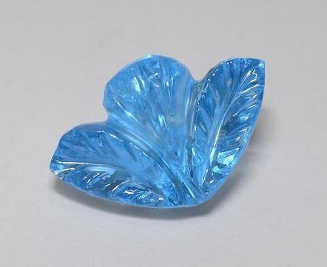 5.50 ct Natural Swiss Blue Topaz, Carved Flower Cut, Transparent, Brazil: 5.50 ct Natural Swiss Blue Topaz, Carved Flower Cut, Transparent, Brazil Natural topaz gemstone weighing 5.50 ct, carved in a flower shape with a Swiss blue color. The gem measures 13.90 x 8.97 x 7.31