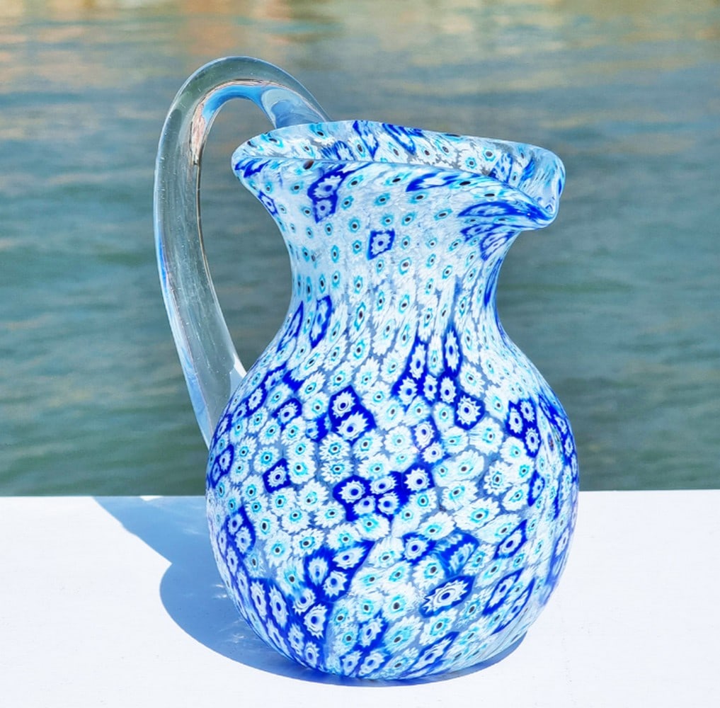 Blue Millefiori Murano Glass Pitcher: Blue Millefiori Murano Glass Pitcher This carafe is crafted using the traditional glassblowing technique, adorned with exquisite murrina decoration. Ideal for daily use, whether serving water, wine,