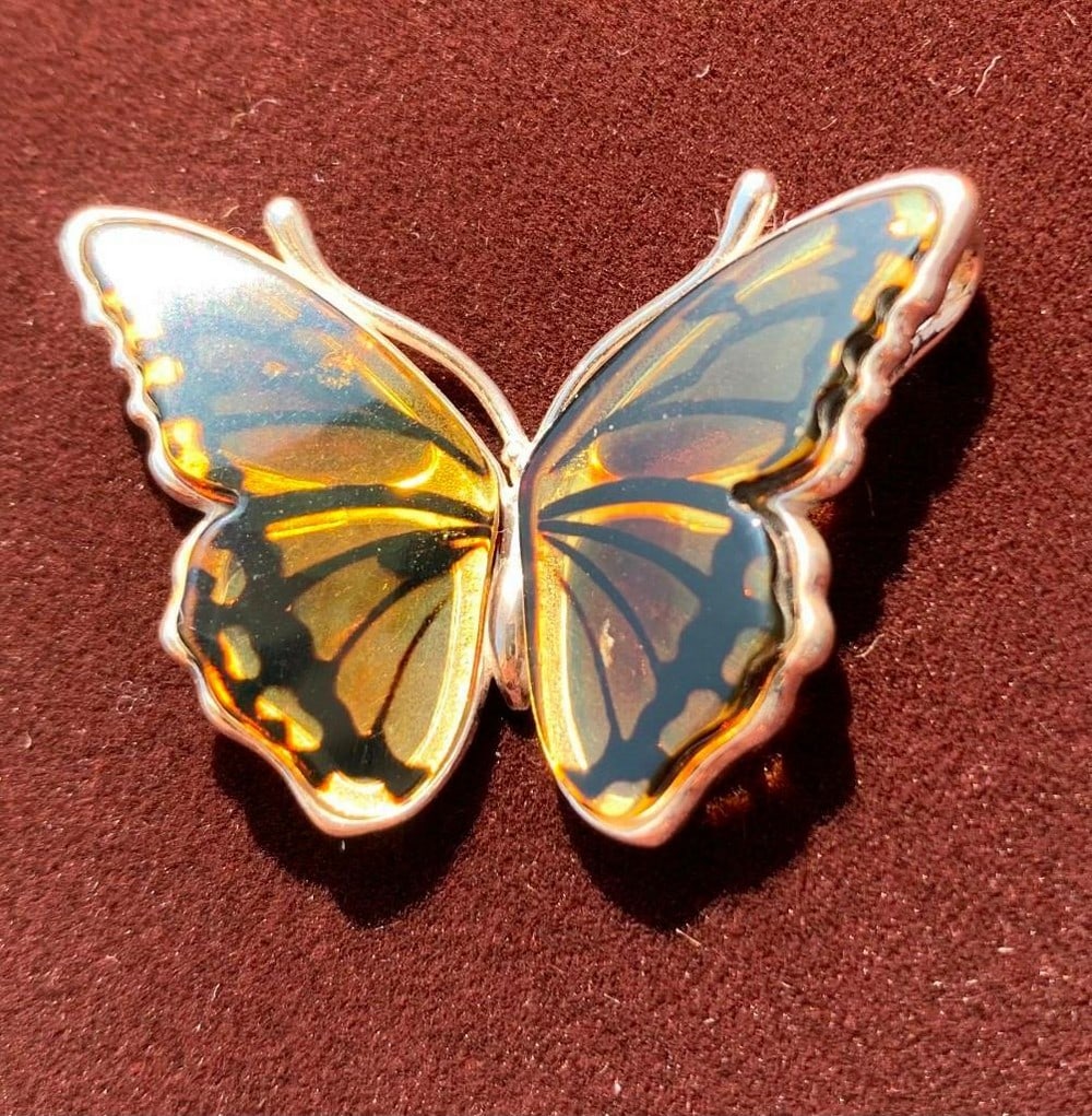 Golden Wings Pendant: Golden Wings Pendant This stunning amber butterfly pendant combines natural elegance with timeless craftsmanship. The warm, honey-toned amber forms the delicate wings of the butterfly, while the