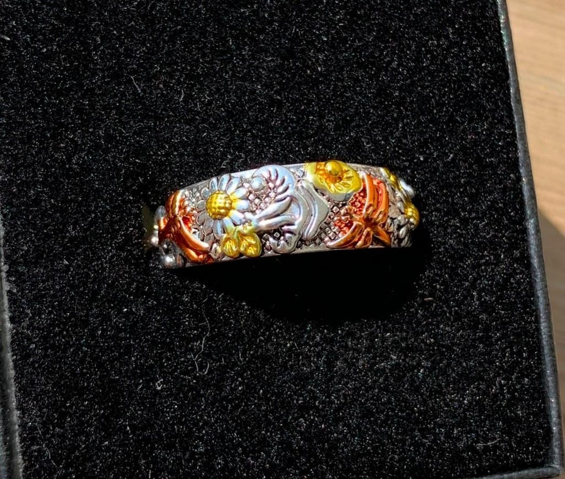 Blooming Flight Ring: Blooming Flight Ring This enchanting ring features intricate flower designs paired with vibrant dragonflies, their delicate wings adorned in bright orange hues. Some of the flowers also shimmer