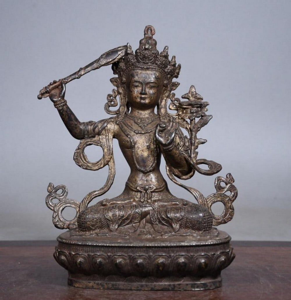 Gilded Copper Sword-Holding Manjusri Buddha Statue: Gilded Copper Sword-Holding Manjusri Buddha Statue This antique Manjusri Buddha statue is a stunning example of traditional Chinese craftsmanship, meticulously handcrafted from pure copper and