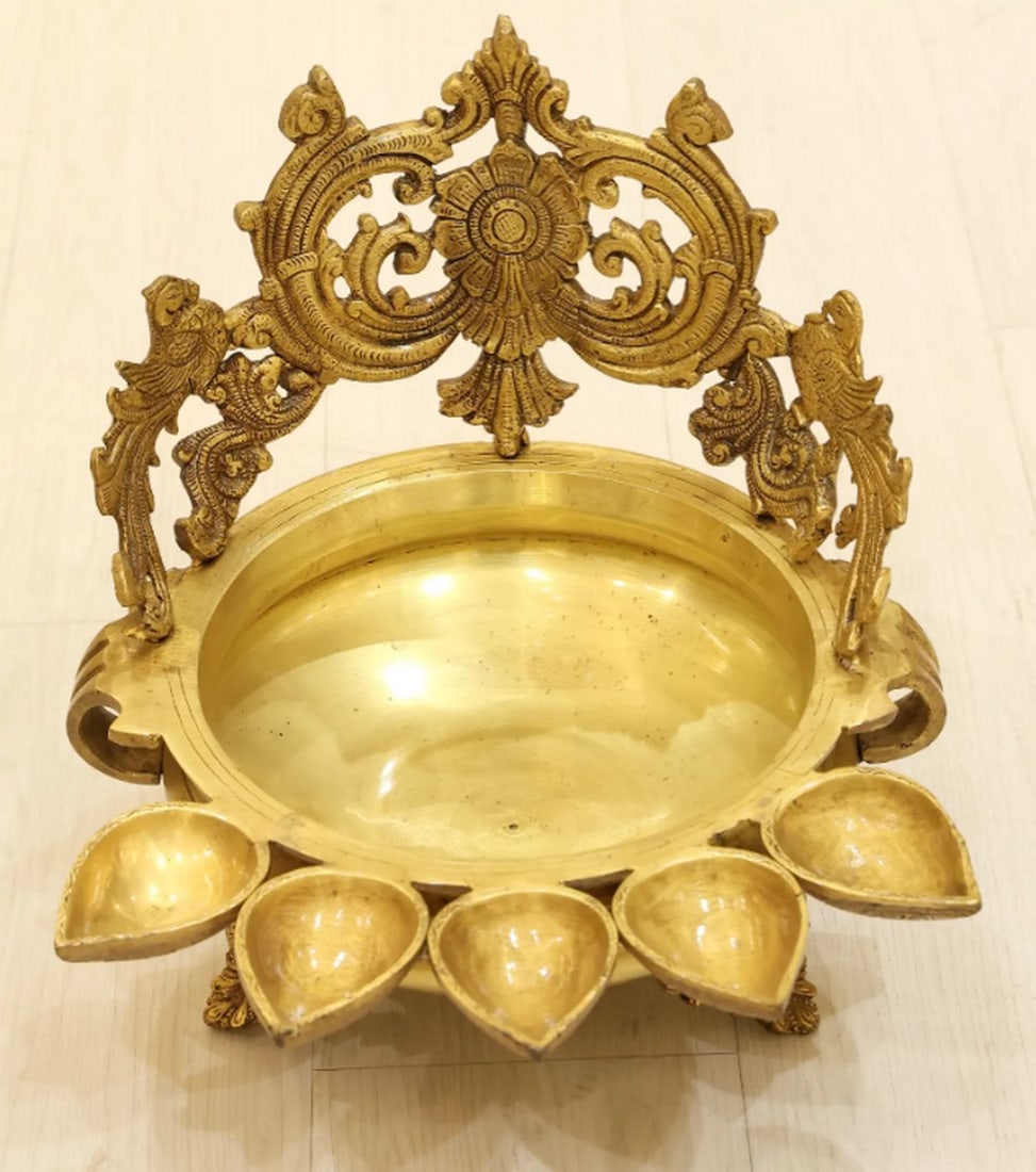 12" Peacock-Design Urli with Lamp Holders: 12" Peacock-Design Urli with Lamp Holders Crafted from brass, this Urli is designed in three sections: a crown with coiled vine patterns and two peacocks, a central wide-mouthed basin, and vine-sh