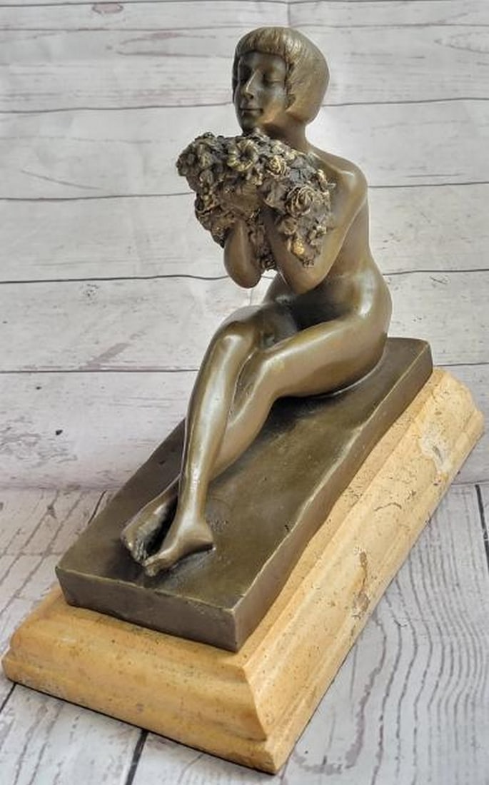 Serenity in Bloom: Nude Girl Holding Flowers Bronze Sculpture: Serenity in Bloom: Nude Girl Holding Flowers Bronze Sculpture Delicate and serene, this reproduction bronze metal sculpture depicts a nude young woman seated gracefully with her legs extended and gen