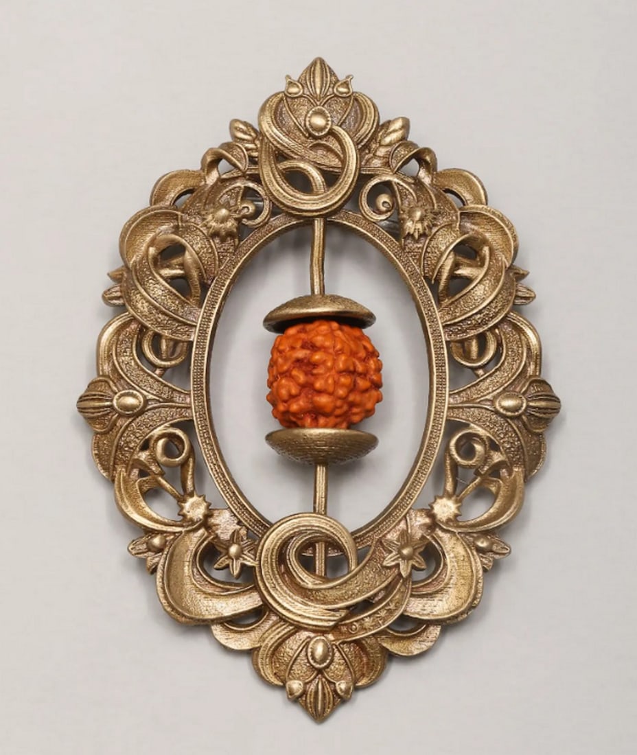 Sacred Rudraksha Floral Brooch: Sacred Rudraksha Floral Brooch Adorn your attire with this beautifully crafted brooch, featuring a calming Rudraksha bead encased in an intricate brass floral frame. The ornate design blends traditio
