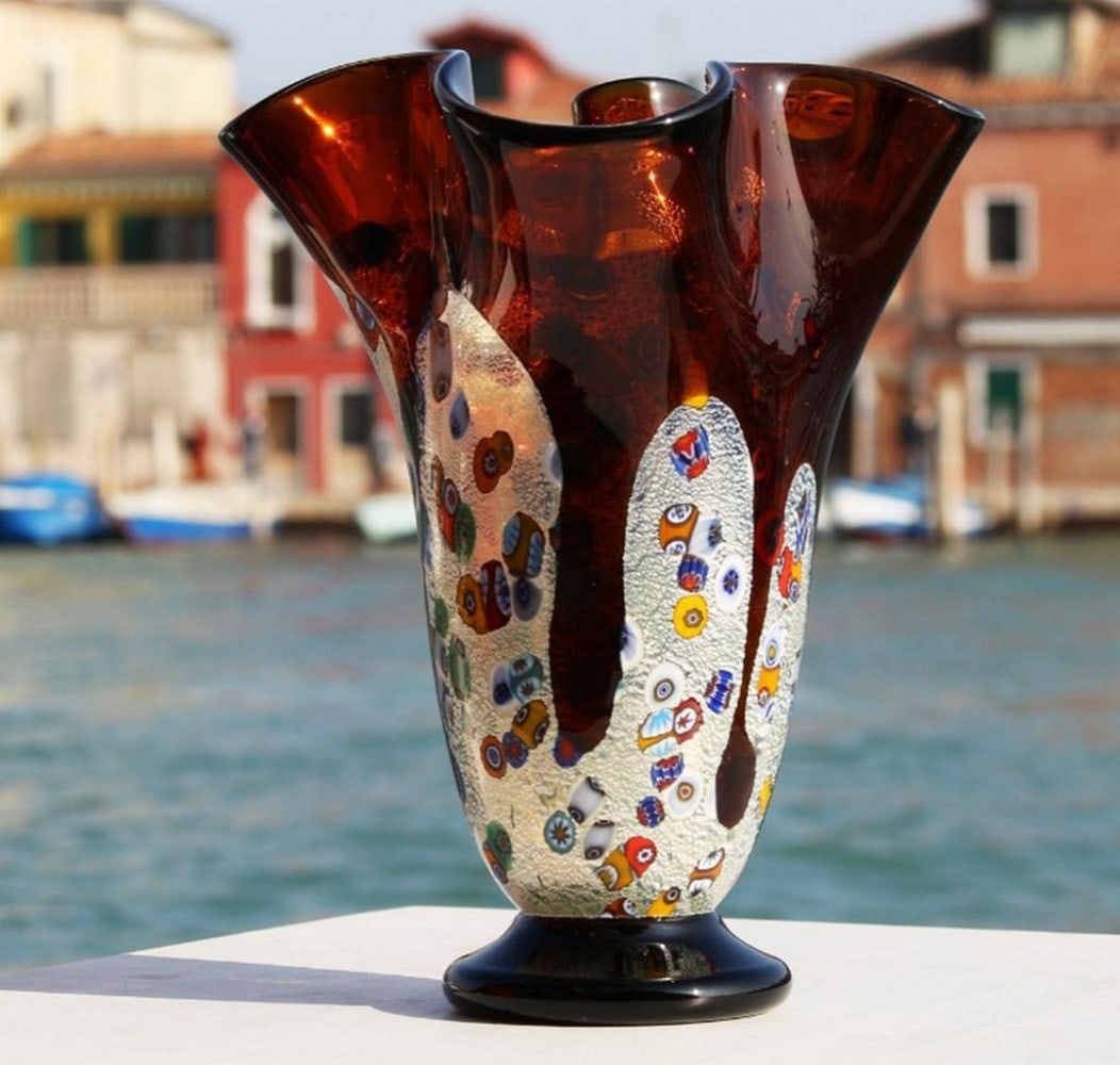 Amber Tulipano Vase with Millefiori and Silver Accents – Murano Glass: Amber Tulipano Vase with Millefiori and Silver Accents – Murano Glass This vase is crafted using the blown glass technique and adorned with silver leaf and vibrant, multicolored murrine. It’s perf