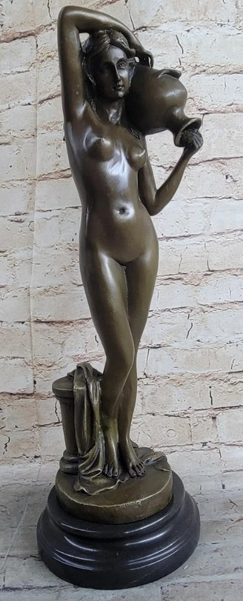 Bronze Nude Woman with Raised Arm Sculpture by Milo - 18" x 7": Bronze Nude Woman with Raised Arm Sculpture by Milo - 18" x 7" This conceptual bronze sculpture by Milo portrays a nude woman standing with one arm raised, holding a vase, her gaze fixed ahead