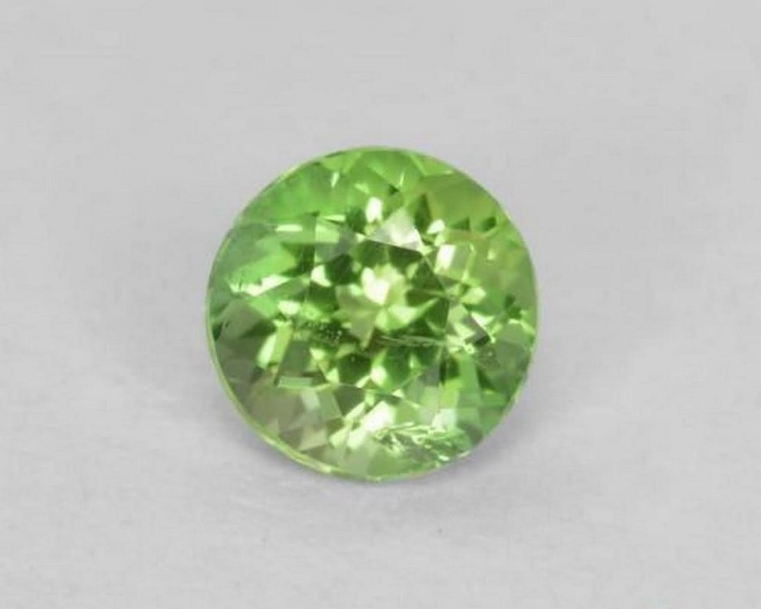 0.19 ct Natural Lively Green Kornerupine, Round Facet, SI, Sri Lanka: 0.19 ct Natural Lively Green Kornerupine, Round Facet, SI, Sri Lanka Natural kornerupine gemstone weighing 0.19 ct, cut in a round facet shape with a lively green color. The gem measures 3.48 x 2.60 m