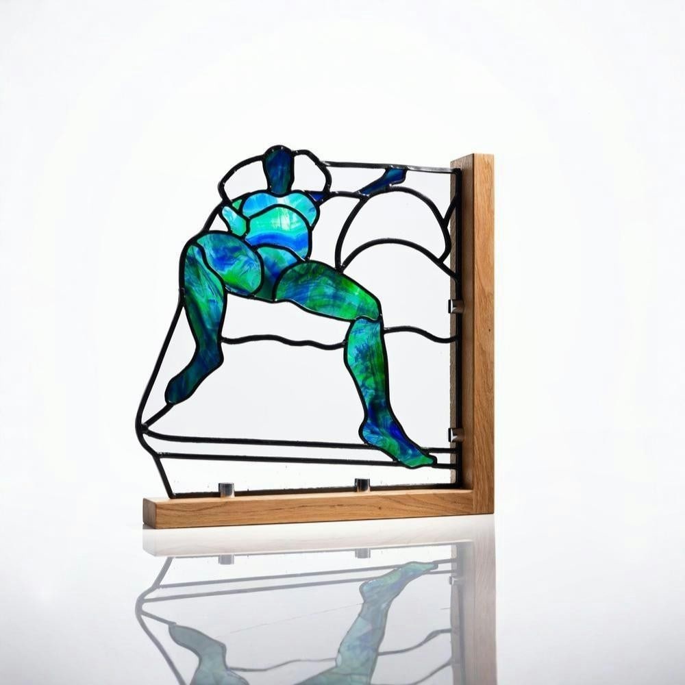“Cleo?? Leaded Stained Glass by Laura Kriefman: “Cleo” Leaded Stained Glass by Laura Kriefman This leaded stained glass artwork depicts a reclining female figure, emphasizing form, balance, and composition. Created using mouth-blown glass a