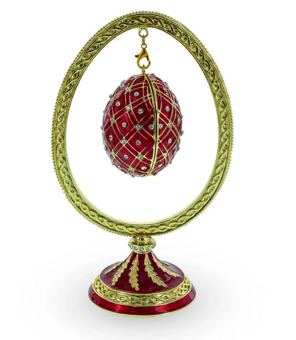 Red Bejeweled Egg Hanging in Display Holder: Red Bejeweled Egg Hanging in Display Holder This sparkling egg is adorned with clear crystals and high-polished enamel with golden trim. It opens on a hinge and has a magnetic closure to keep the box