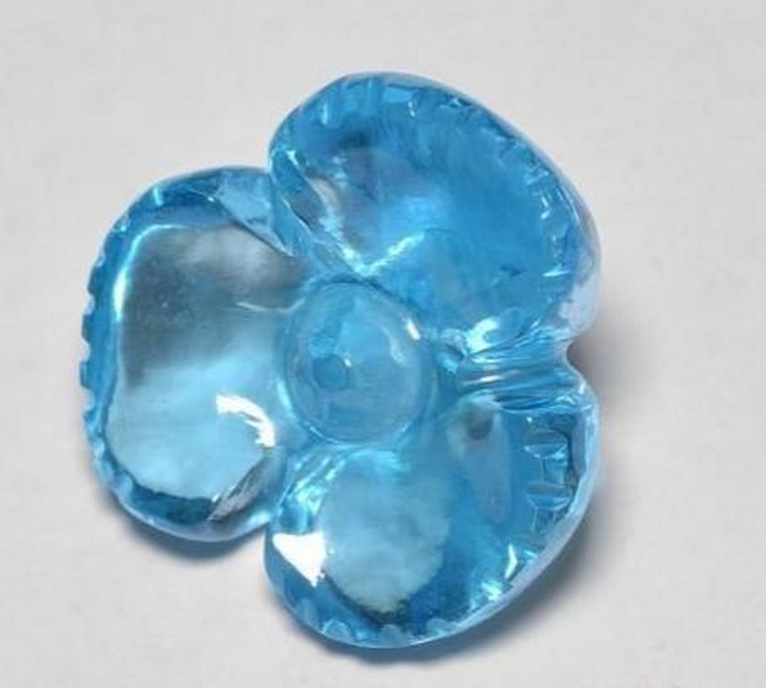 Swiss Blue Topaz Carved Flower Gemstone: Swiss Blue Topaz Carved Flower Gemstone Brilliant and refreshing, this loose gemstone is expertly carved into a delicate flower from radiant Swiss Blue topaz. The vivid sky-blue hue sparkles with cla