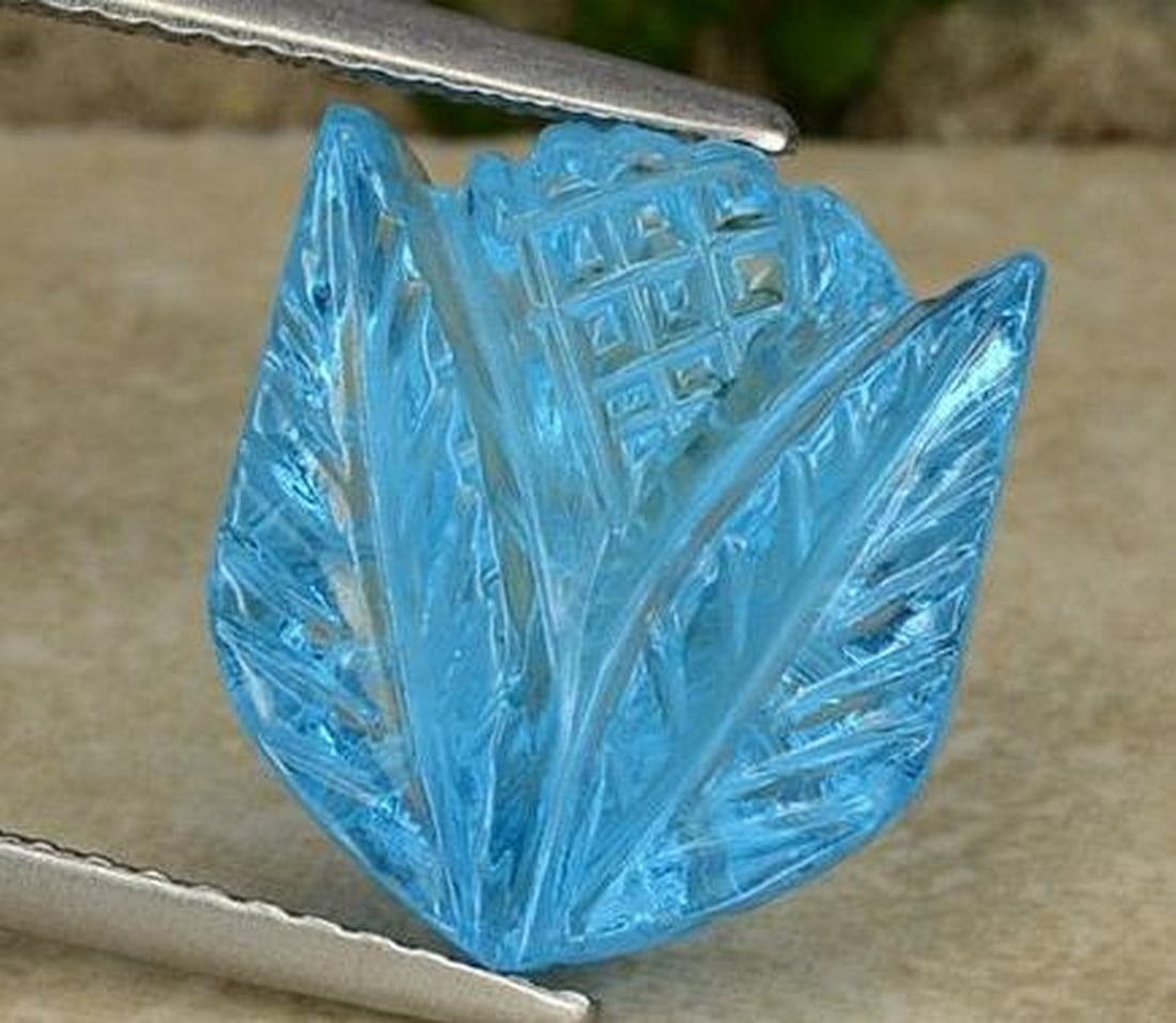 Swiss Blue Topaz Carved Flower Gemstone: Swiss Blue Topaz Carved Flower Gemstone This dazzling loose gemstone is expertly carved into the shape of a delicate flower from radiant Swiss Blue topaz. The vivid blue hue shimmers with clarity
