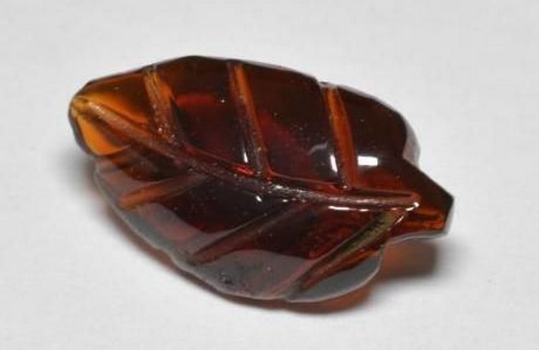 Loose Pyrope Garnet Dark Red Hand-Carved Leaf Gemstone: Loose Pyrope Garnet Dark Red Hand-Carved Leaf Gemstone Rich and refined, this loose Pyrope Garnet is expertly carved into the shape of a delicate leaf, showcasing a deep, dark red hue that glows