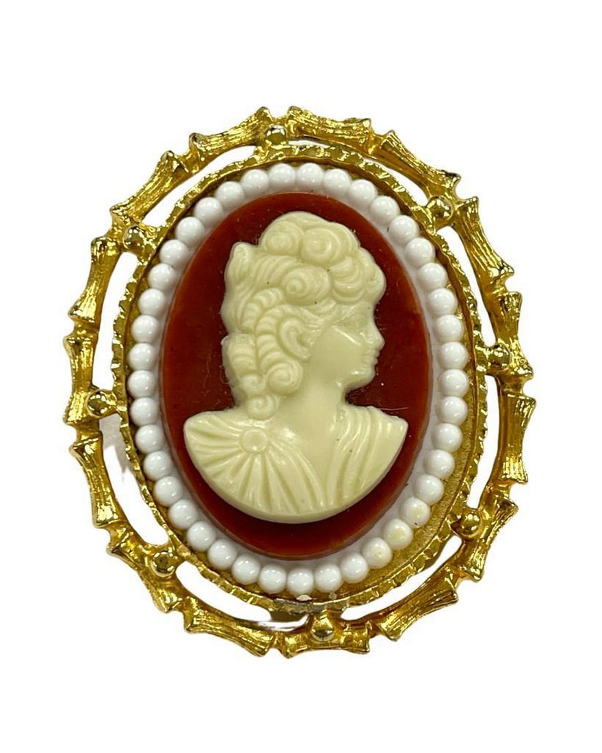 Gold Cameo Brooch with Pearls on Crimson Canvas: Gold Cameo Brooch with Pearls on Crimson Canvas Elevate your style with our opulent Gold Cameo Brooch. Delicately carved against a crimson canvas and framed in gold, adorned with pearls, it effortless