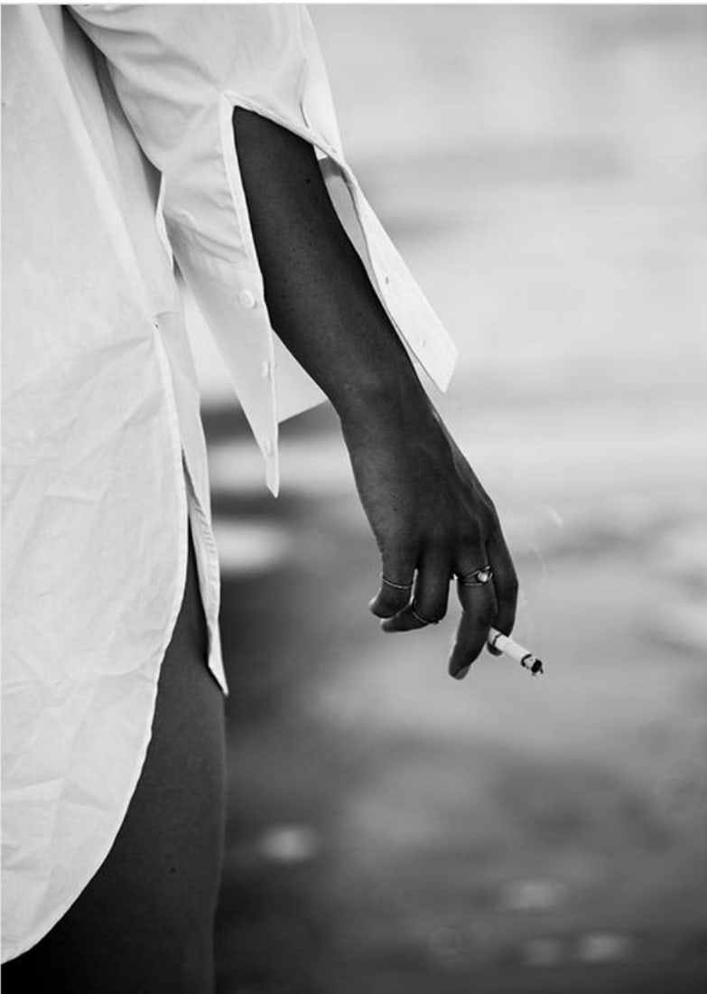 Part Way Through a Smoke on the Beach Poster Print: Part Way Through a Smoke on the Beach Poster Print Girl in a white shirt holding a cigarette standing by the water. Close-up photograph in black & white. Perfect poster to complete your gallery wa