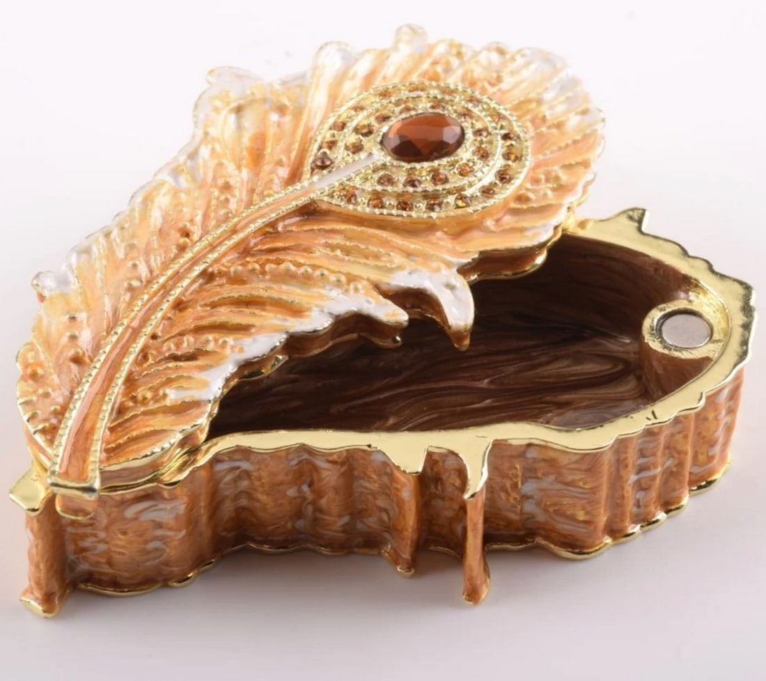 Golden Feather Trinket Box: Golden Feather Trinket Box Each crystal is handpicked and precisely placed on the box. It has a magnetic fastener to secure closure. Dimensions: 2.9"L x 4.1"W x 2.4"H View Photos For Furth